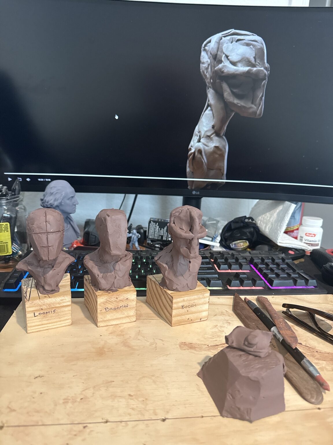 Clay portrait studies below a digital sculpture reference