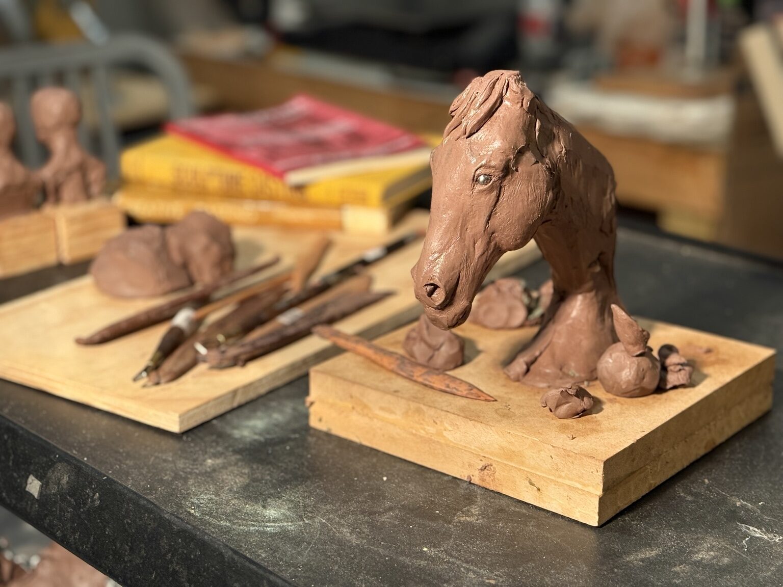Clay horse study with sculpting tools on a studio table